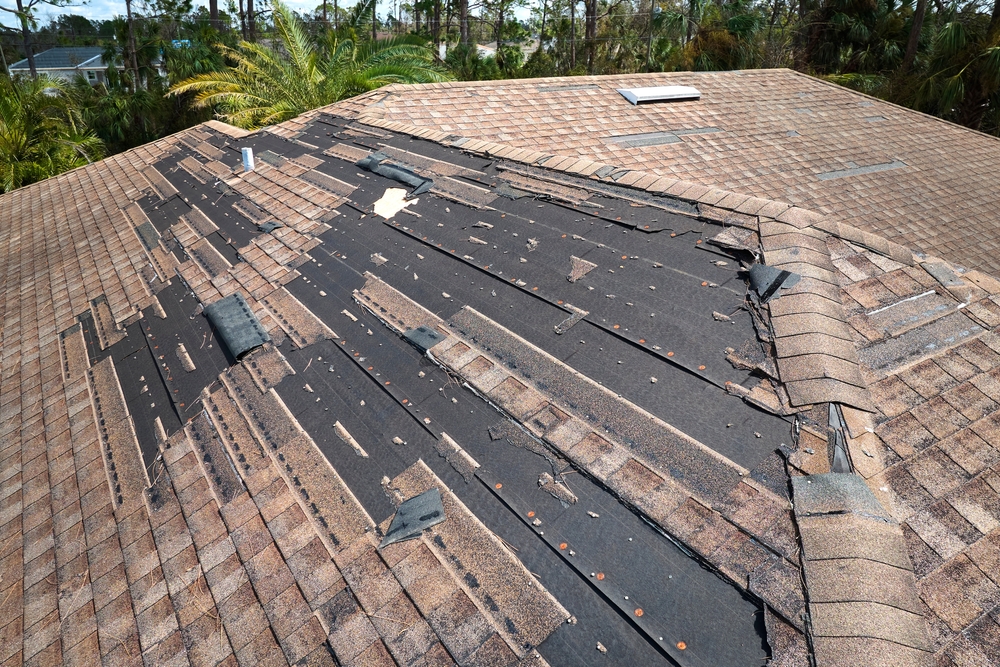 Wind,damaged,house,roof,with,missing,asphalt,shingles,after,hurricane