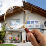 Close Up,of,person's,hand,holding,magnifying,glass,over,luxury,house