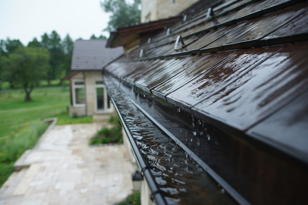 Rain,flowing,down,a,tile,roof,into,gutter